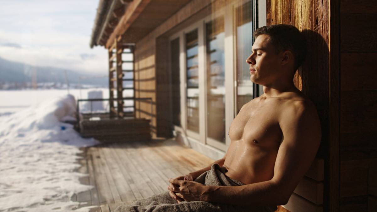 Mann sitzt im Winter vor Sauna