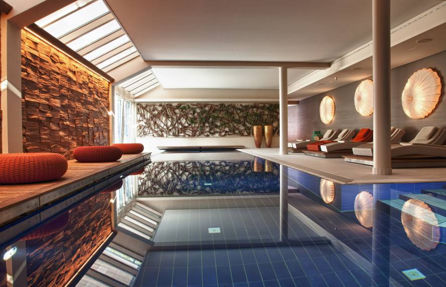 Indoor-Pool mit Liegen und Sitzmöglichkeiten im Strandhotel am Weissensee