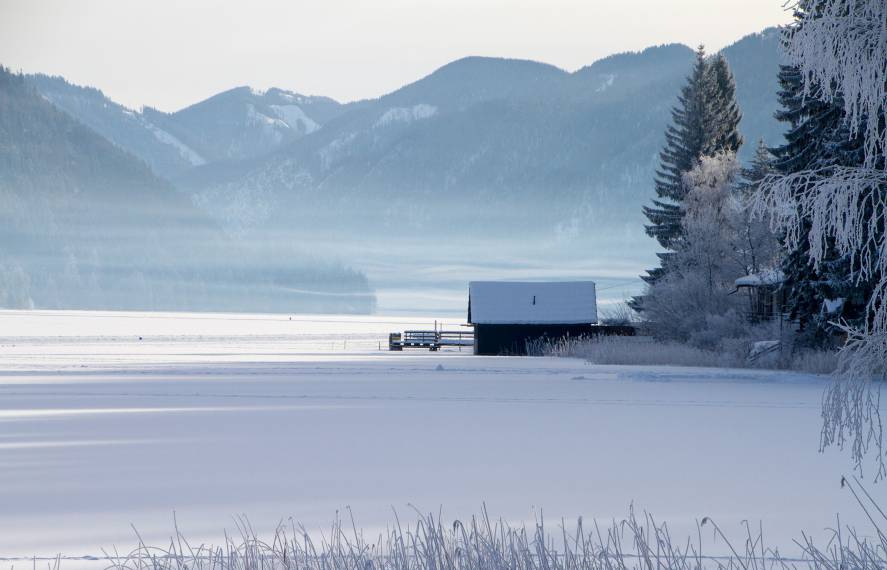 Zugefrorener Weissensee umgeben von einer Schneelandschaft