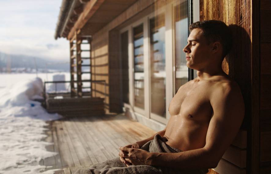 Mann sitzt im Winter vor Sauna