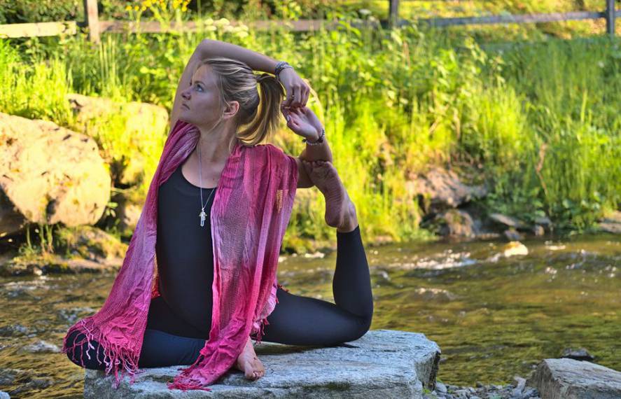 Frau praktiziert Yoga am Fluss