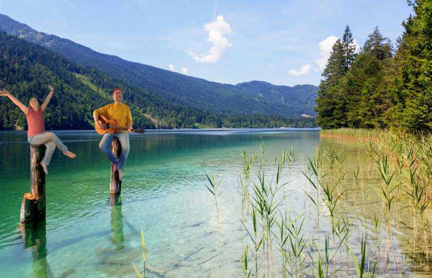 Personen sitzen auf Stegpfosten am Weissensee