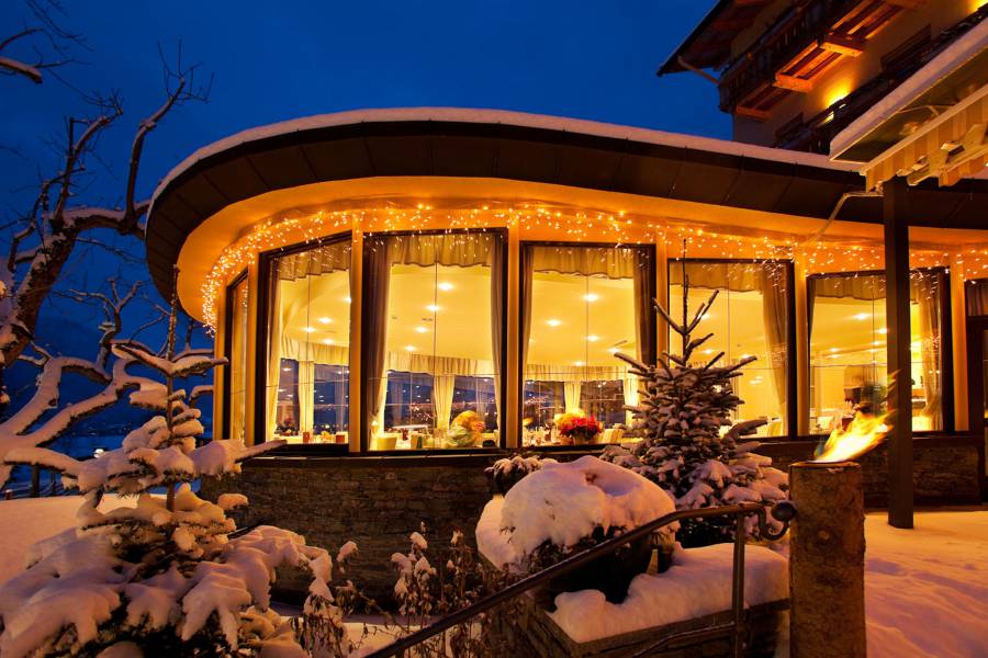 Außenansicht des beleuchteten Restaurants bei Nacht Strandhotel am Weissensee