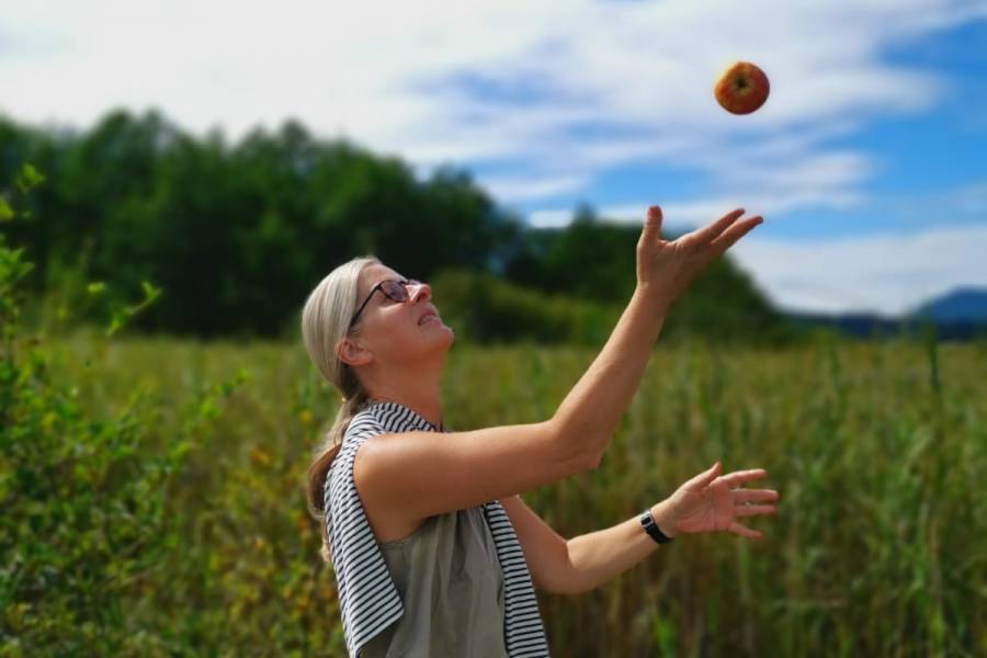 Petra Sölle wirft einen Apfel in die Luft auf dem Feld