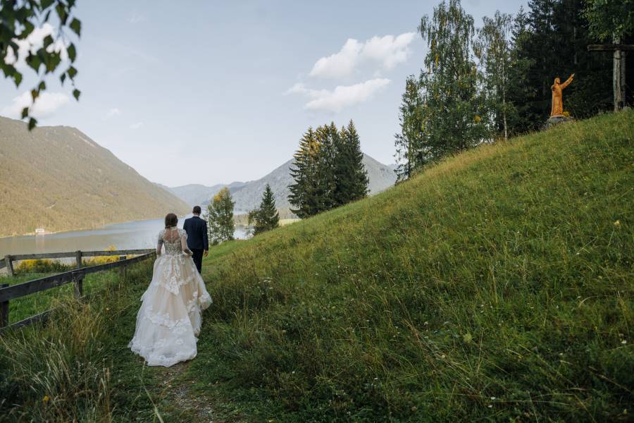Brautpaar läuft über Wiese bei Weissensee